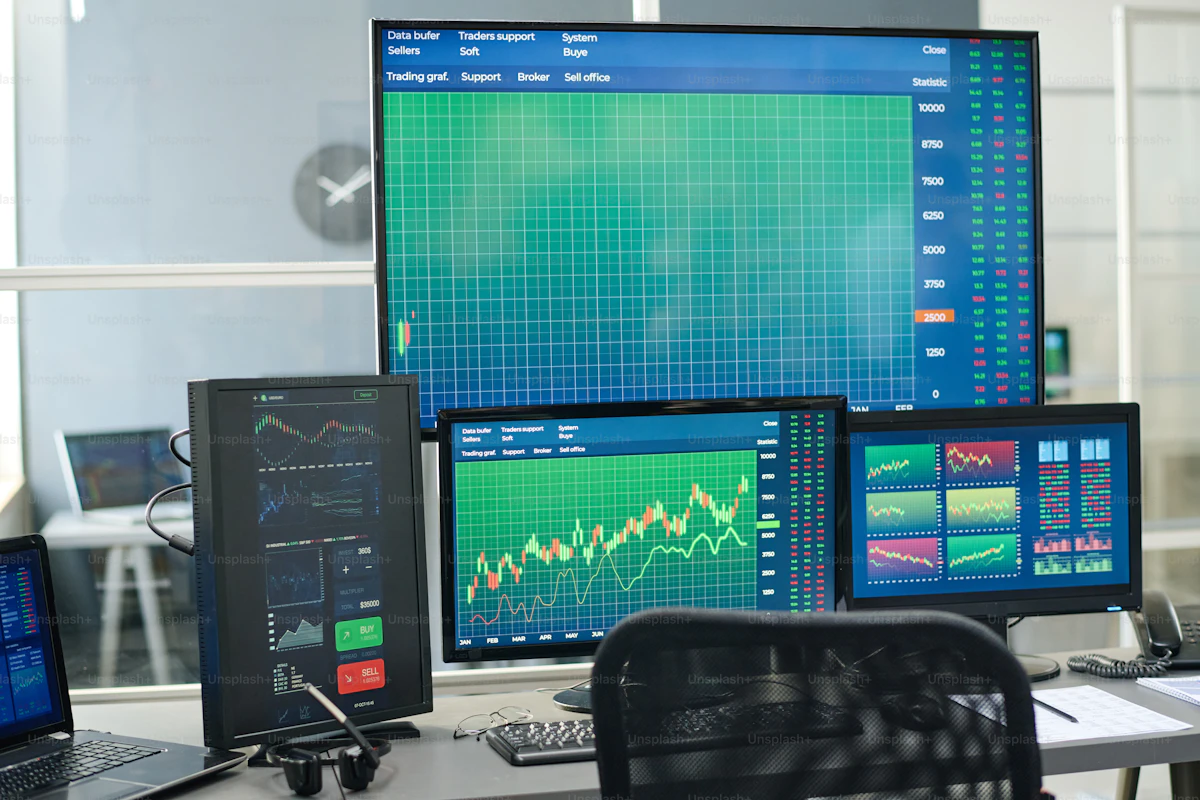 Modern office workspace with desktop monitors showing financial graphs, representing the data behind a personal trainer software comparison
