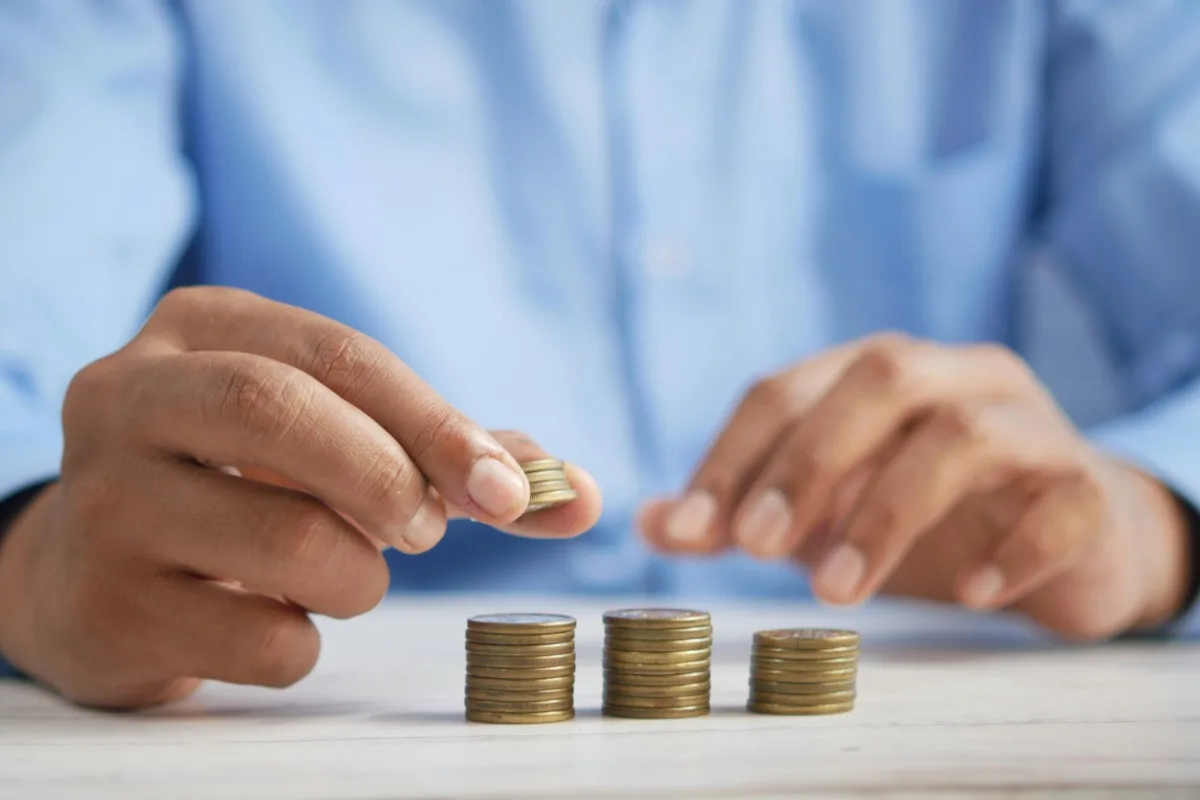 Person stacking coins representing recurring monthly revenue for personal trainers