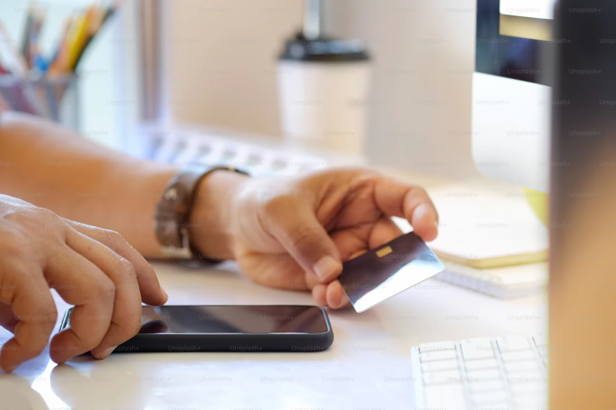 Person paying with a credit card on a mobile phone, representing online payments for personal trainers